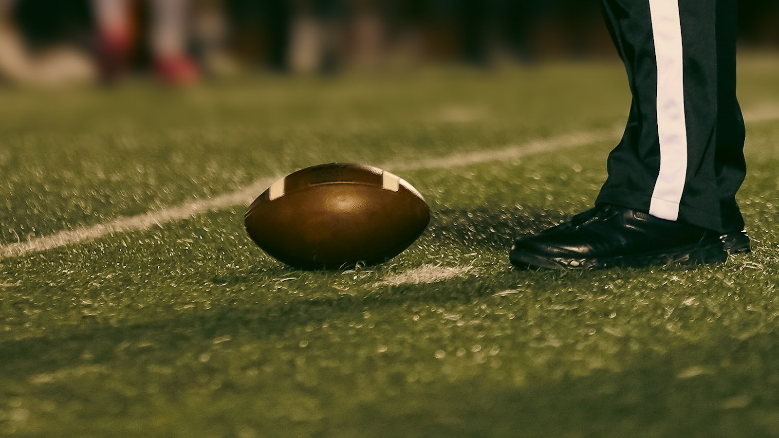 American football beside a football official's foot, ready for kickoff